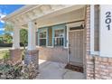 Inviting front porch featuring brick columns, white trim, and a stylish entrance door with a small porch window at 201 Bog Hill Ln, Cary, NC 27519
