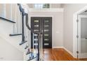 Bright foyer showcases a hardwood floor, staircase with black railing and glass-paneled front door at 208 W Camden Forest Dr, Cary, NC 27518