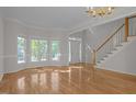 Bright, spacious living room featuring hardwood floors, large windows, and a classic chandelier at 2309 Clerestory Pl, Raleigh, NC 27615