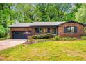 Charming brick home featuring an attached garage, manicured lawn, and inviting front entrance with vibrant flowerbeds at 2509 Elderwood Ln, Burlington, NC 27215