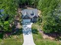 Aerial view of a home with a long driveway surrounded by lush trees and a well-maintained yard at 3627 River Watch Ln, Franklinton, NC 27525