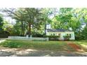 Inviting single-story home with a brick walkway, green lawn, and white picket fence under mature shade trees at 409 Green St, Sanford, NC 27330