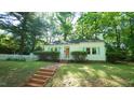 Charming white home featuring blue shutters, brick steps, and a quaint white picket fence at 409 Green St, Sanford, NC 27330