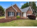 Red brick home with black shutters and manicured lawn featuring mature trees at 411 Westhampton Dr, Burlington, NC 27215