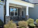 Inviting covered porch with stone pillars and seating area, perfect for relaxing outdoors at 47 Scarlet Bell Dr, Youngsville, NC 27596