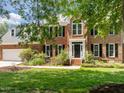 A stately brick home with a classic black front door, white trim, and manicured landscaping at 5 Bobby Parker Pl, Durham, NC 27703