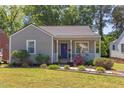 Charming home featuring a well-manicured front lawn with mature trees, landscaping, and a welcoming front porch at 508 E Trinity Ave, Durham, NC 27701