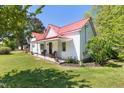 Charming home featuring a red metal roof, inviting front porch with seating, and well-manicured green lawn at 5423 Nc-39, Selma, NC 27576