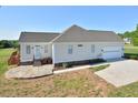 Rear exterior with a stone patio, deck, and three-car garage with paved driveway at 55 Derwin Dr, Timberlake, NC 27583