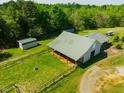 Aerial of the barn featuring fenced pasture land and convenient outbuildings at 5916&5918 Laws Farm Rd, Rougemont, NC 27572
