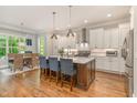 Open-concept kitchen featuring a large island with barstool seating, white cabinetry, and stainless steel appliances at 7108 Carries Reach Way Way, Raleigh, NC 27614
