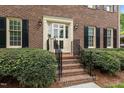 Inviting brick entryway with manicured shrubs, wrought iron railing, and a classic front door at 804 Warwick Ct, Burlington, NC 27215