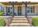 Inviting front porch with stone steps, wooden beams, seating, and a decorative front door at 1012 Wandering Way, Rolesville, NC 27571