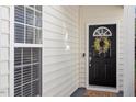 Elegant front door with decorative wreath and welcome mat, complemented by sidelight windows at 1208 Copper Creek Dr, Durham, NC 27713