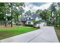 Lovely two-story white home with long driveway and three car garage surrounded by lush landscaping at 1241 Keith Rd, Wake Forest, NC 27587