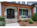Inviting front porch with wood columns, brick accents, a bench, and beautifully landscaped surroundings at 1241 Keith Rd, Wake Forest, NC 27587