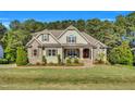 Inviting two-story home with a covered porch, stone accents, and professionally landscaped yard at 128 Paraggi Ct, Clayton, NC 27527