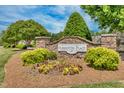 Abbington Place entrance sign, featuring stone pillars, lush landscaping, and seasonal flowers at 1410 Osborne Dr, Burlington, NC 27215