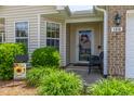 Inviting front porch with door wreath, accent furniture, a Welcome sign, and manicured landscaping at 1410 Osborne Dr, Burlington, NC 27215