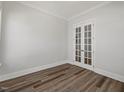 A bedroom with neutral walls, wood-look floors, and french doors leading to another room at 1513 Armscroft Lane, Apex, NC 27502