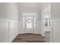 Bright foyer featuring a modern front door, wood-look floors, and classic wainscoting at 1513 Armscroft Lane, Apex, NC 27502