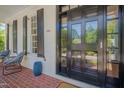 Inviting front door with detailed glass panels, flanked by seating area on the red brick porch at 2306 Byrd St, Raleigh, NC 27608