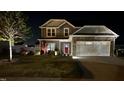 Exterior view of a two-story home at night featuring an attached garage, well-manicured lawn, and landscape lighting at 267 Darecrest Ln, Wendell, NC 27591