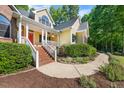 Beautiful home featuring a welcoming front porch with brick stairs and walkway surrounded by manicured landscaping at 3035 Tavistock Dr, Durham, NC 27712