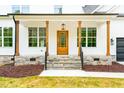 Inviting front porch with wood columns and stone base, leading to a charming wood front door at 3281 Phillips Chapel Rd, Haw River, NC 27258