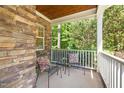 Relaxing covered front porch with cozy seating, stone accent wall, and serene wooded view at 3612 Carriage Dr, Raleigh, NC 27612