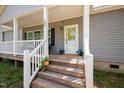 Inviting front porch with a welcoming door, decorative wreath, and blooming potted flowers at 380 Perdues Rd, Louisburg, NC 27549