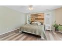 Stylish bedroom with a reclaimed wood accent wall, neutral tones, and abundant natural light at 408 Blooming Meadows Rd, Holly Springs, NC 27540