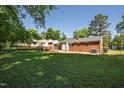Large backyard with lush green grass, mature trees, and a view of the rear exterior of the brick home at 430 Fenton St, Raleigh, NC 27604