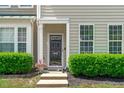 Close-up of a charming townhouse entrance with a glass screen door, potted plants, and manicured bushes at 4535 Sugarbend Way, Raleigh, NC 27606