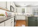 Open kitchen with white cabinets, an island, stainless appliances, and sleek countertops at 5213 Holly Ridge Farm Rd, Raleigh, NC 27616
