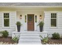 Inviting front porch with a wreath, black planters, and freshly painted white brick steps at 5642 Falkirk Dr, Durham, NC 27712