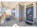 Close-up of front porch with a comfortable swing, stylish stone accents, and a charming blue front door at 6633 Penfield St, Wake Forest, NC 27587