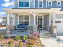 Inviting front porch with a cozy swing, stone pillars, decorative plants, and a charming entrance at 6633 Penfield St, Wake Forest, NC 27587