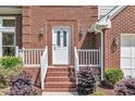Charming front entrance with brick steps, decorative shrubs, and stylish sconces on either side of the door at 7 Bonham Ct, Durham, NC 27703