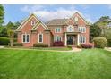 Stately brick home with manicured lawn, mature trees, and charming architectural details at 712 Evanvale Ct, Cary, NC 27518