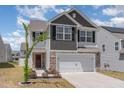 Charming two-story home with a stone and gray exterior, complemented by a well-manicured front yard and a spacious two-car garage at 729 Little Patch St, Zebulon, NC 27597