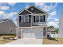 Charming two-story home with a stone and gray exterior, complemented by a well-manicured front yard and a spacious two-car garage at 729 Little Patch St, Zebulon, NC 27597
