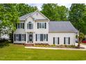 Charming two-story home featuring a manicured lawn, mature trees, and classic design elements at 8600 Clivedon Dr, Raleigh, NC 27615