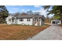 A charming white brick home complemented by a spacious driveway leading to a detached garage at 900 Roxboro Road, Oxford, NC 27565