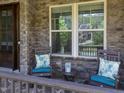 Inviting front porch with stone facade, rocking chairs, and leafy decorative pillows at 1037 Lila Ln, Raleigh, NC 27614