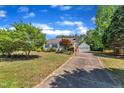 Long driveway leads to a well-maintained home with a detached garage and lush trees at 1112 Turner Farms Rd, Garner, NC 27529