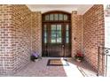 Inviting brick front porch with a dark wood door, glass panels, and potted flowers at 12508 Angel Falls Rd, Raleigh, NC 27614
