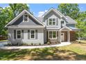 Inviting two-story home showcasing gray siding and stone accents, framed by lush greenery and a welcoming walkway at 2405 Pearces Rd, Zebulon, NC 27597