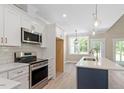 Stylish kitchen featuring white cabinets, stainless steel appliances, quartz countertops, and an island with pendant lighting at 2405 Pearces Rd, Zebulon, NC 27597