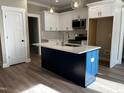 Modern kitchen featuring white cabinets, navy blue island, stainless steel appliances, and stone countertops at 2405 Pearces Rd, Zebulon, NC 27597